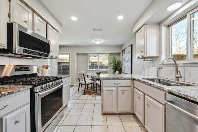 kitchen featuring tasteful backsplash, visible vents, stainless steel appliances, a sink, and light tile patterned flooring