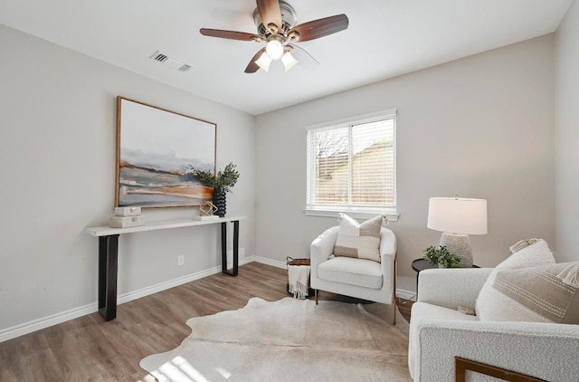 living area with baseboards, visible vents, ceiling fan, and wood finished floors