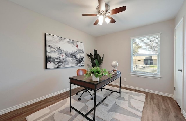 office space featuring a ceiling fan, baseboards, and wood finished floors