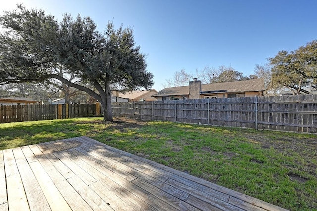 wooden terrace with a lawn and a fenced backyard