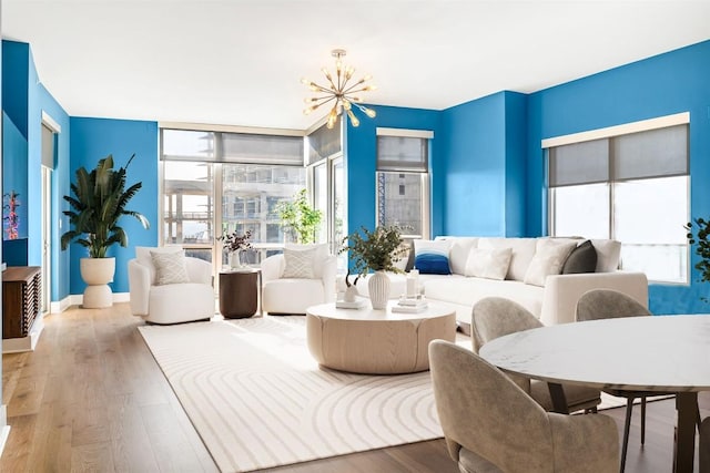 living room featuring baseboards, wood finished floors, and a notable chandelier