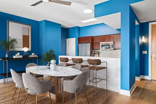 dining room featuring ceiling fan, wood finished floors, and baseboards