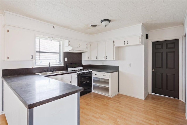 kitchen with range with gas stovetop, dark countertops, white cabinets, and a sink