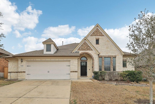 french country inspired facade featuring a garage, stone siding, driveway, and a shingled roof