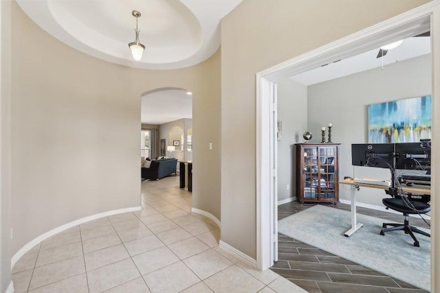 office space with arched walkways, baseboards, and light tile patterned floors