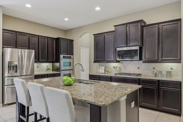2629 Estefania Ln, Round Rock, TX 78665 - kitchen with appliances with stainless steel finishes, a sink, light stone counters, light tile patterned floors, and a center island with sink