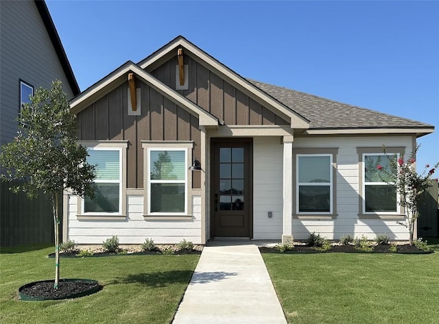 view of front of home with board and batten siding, roof with shingles, fence, and a front lawn