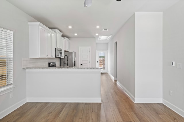 kitchen with light wood-style flooring, white cabinetry, stainless steel appliances, and backsplash