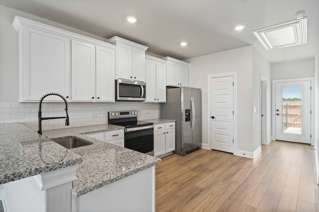 kitchen featuring appliances with stainless steel finishes, a sink, and white cabinetry