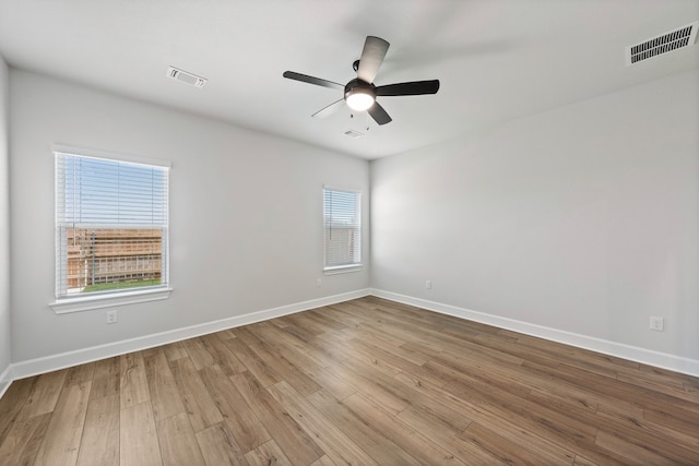 empty room with a ceiling fan, baseboards, visible vents, and wood finished floors