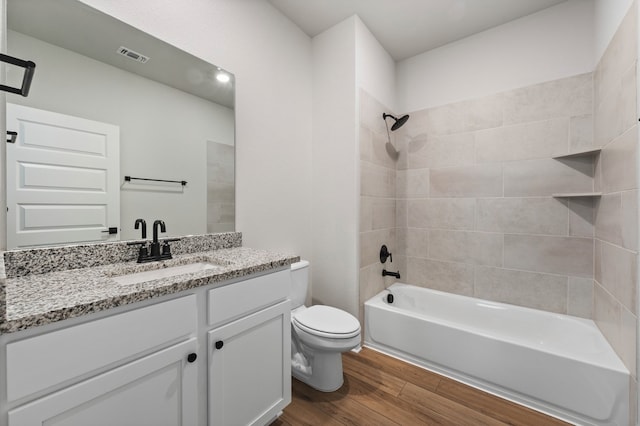 full bath featuring visible vents, toilet, washtub / shower combination, vanity, and wood finished floors