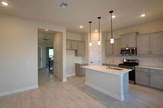 kitchen with decorative backsplash, light wood-style flooring, appliances with stainless steel finishes, gray cabinetry, and a sink