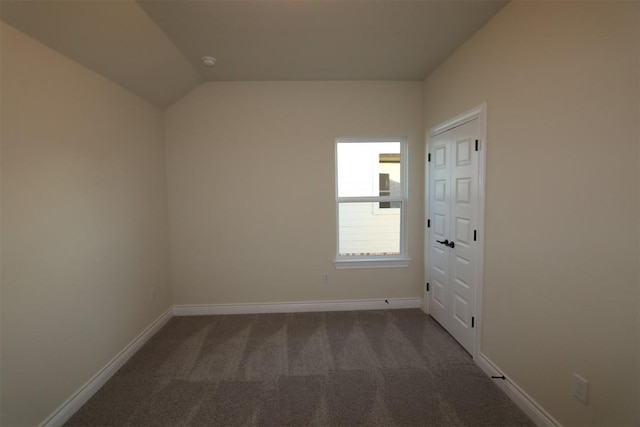 carpeted spare room featuring baseboards and vaulted ceiling