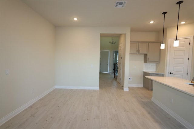 kitchen featuring baseboards, visible vents, gray cabinets, light wood-type flooring, and backsplash