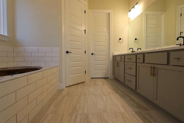 full bathroom featuring tiled tub and vanity