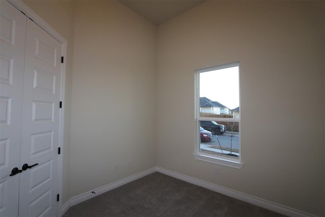 empty room with dark carpet and baseboards