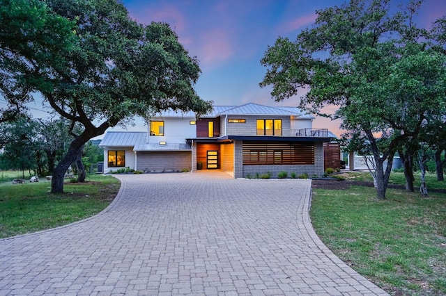 24710 Fossil Trl, Spicewood, TX 78669 - modern home featuring curved driveway, a standing seam roof, a front lawn, metal roof, and a balcony