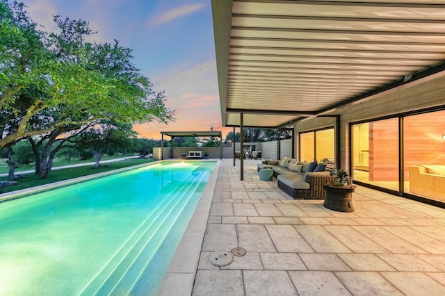 pool at dusk featuring a fenced in pool, outdoor lounge area, and a patio