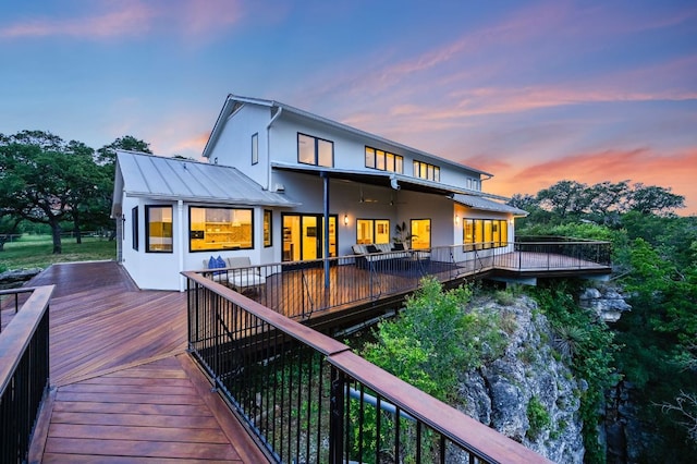 rear view of house featuring a wooden deck, stucco siding, metal roof, and a standing seam roof