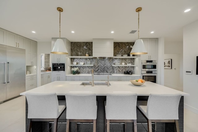 kitchen featuring visible vents, backsplash, light countertops, appliances with stainless steel finishes, and a sink