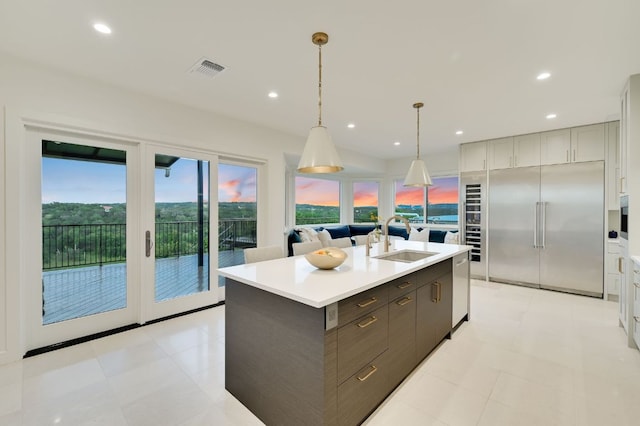 kitchen featuring visible vents, a kitchen island with sink, a sink, appliances with stainless steel finishes, and light countertops