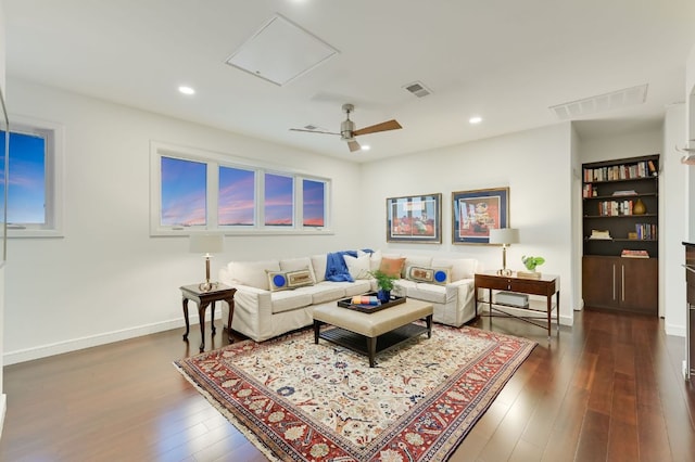 living room with dark wood finished floors, visible vents, attic access, and baseboards