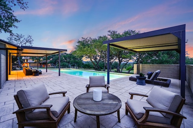 patio terrace at dusk with a fenced in pool and an outdoor hangout area