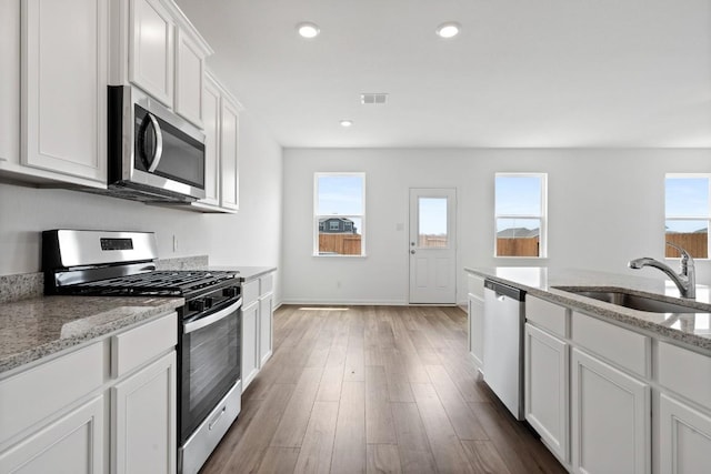 kitchen featuring appliances with stainless steel finishes, wood finished floors, white cabinetry, a sink, and recessed lighting