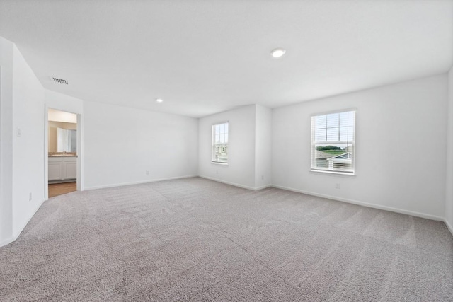 empty room featuring recessed lighting, light carpet, visible vents, and baseboards