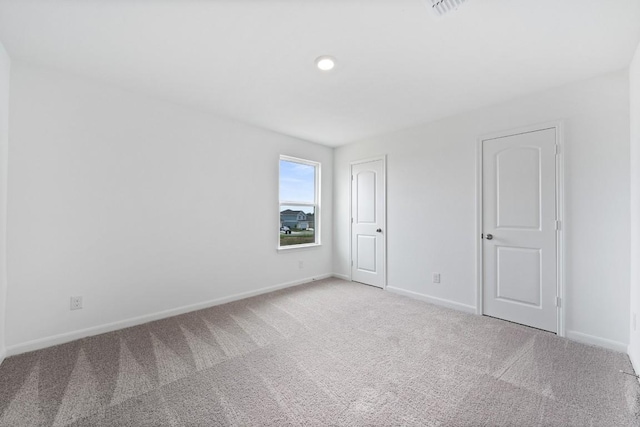 spare room with light carpet, visible vents, and baseboards