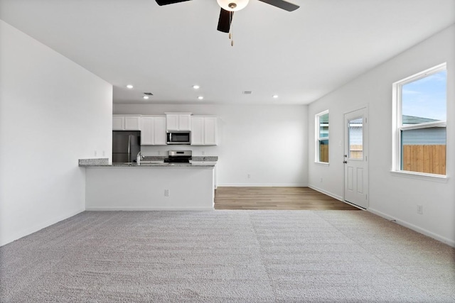 unfurnished living room featuring baseboards, light colored carpet, a ceiling fan, and recessed lighting