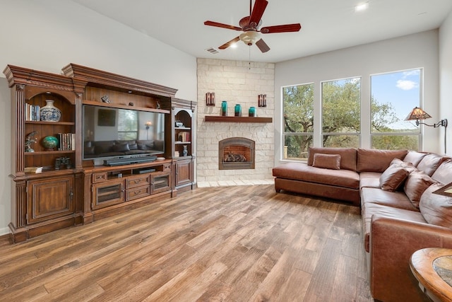 living room with ceiling fan, a fireplace, wood finished floors, and visible vents