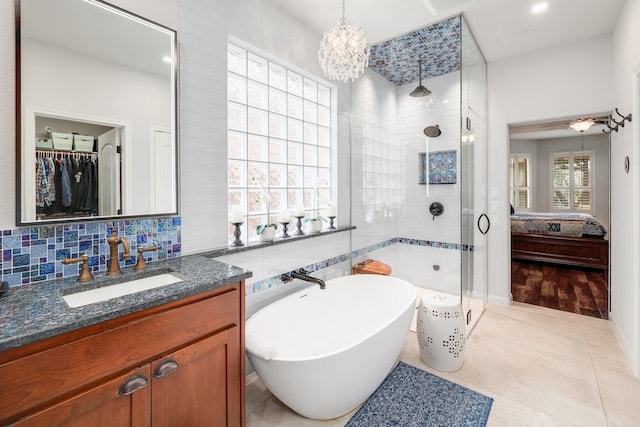 11708 Palisades Pkwy, Austin, TX 78732 - ensuite bathroom featuring a shower stall, a freestanding bath, vanity, a walk in closet, and decorative backsplash