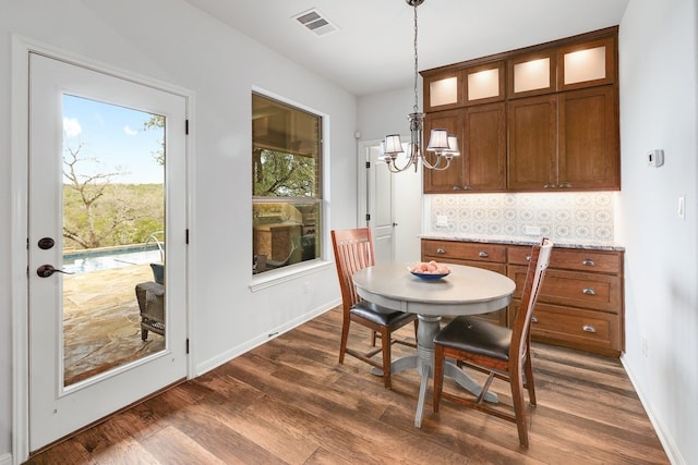 dining room with dark wood-style floors, a notable chandelier, visible vents, and baseboards