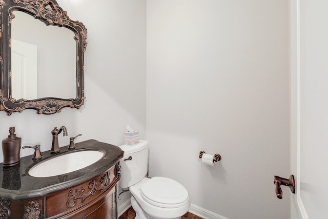 half bathroom featuring baseboards, vanity, and toilet