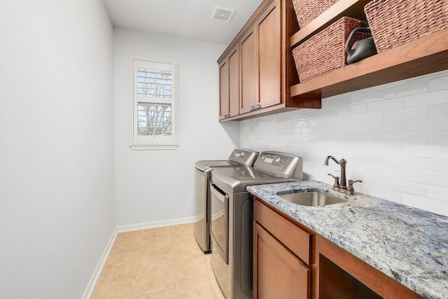 laundry area with cabinet space, visible vents, a sink, separate washer and dryer, and baseboards