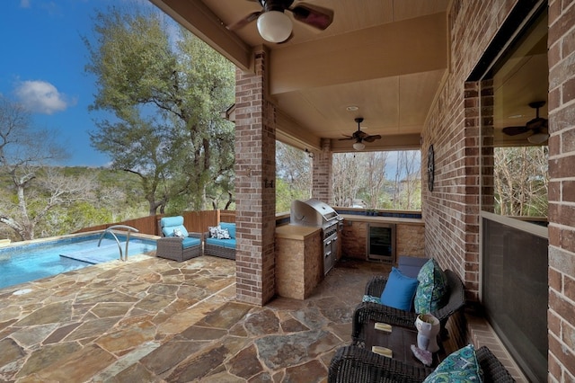 view of patio / terrace featuring wine cooler, grilling area, an outdoor kitchen, a ceiling fan, and an outdoor living space