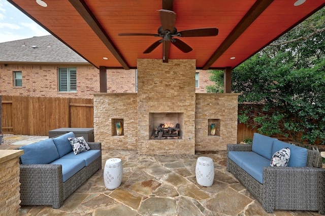 view of patio / terrace with an outdoor living space with a fireplace, fence, and a ceiling fan