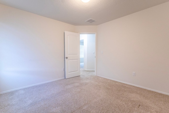 unfurnished room with visible vents, light carpet, a textured ceiling, and baseboards