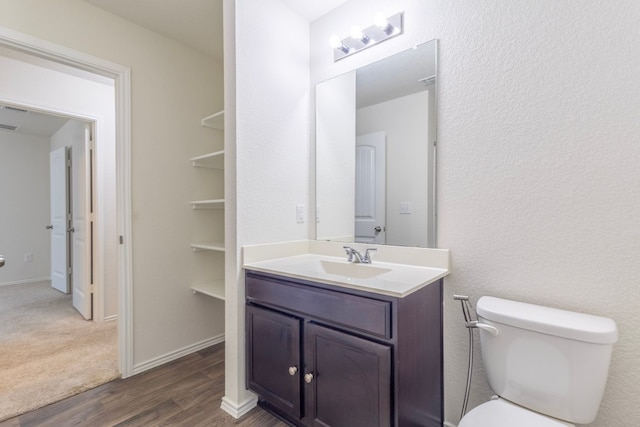 bathroom with toilet, wood finished floors, visible vents, vanity, and baseboards