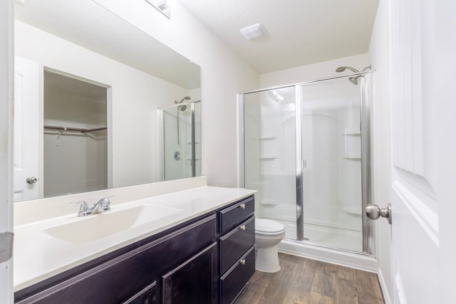 bathroom featuring vanity, wood finished floors, a shower stall, and toilet