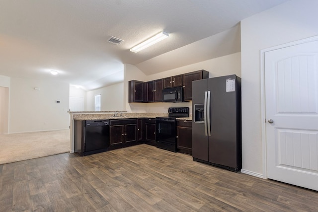 kitchen with visible vents, vaulted ceiling, dark brown cabinets, black appliances, and a sink