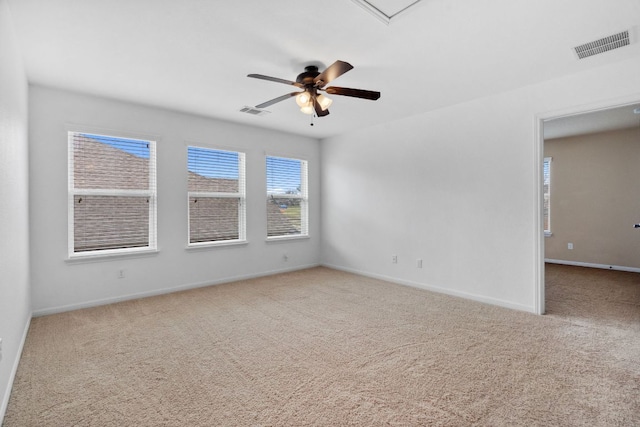 carpeted spare room featuring baseboards, visible vents, and ceiling fan