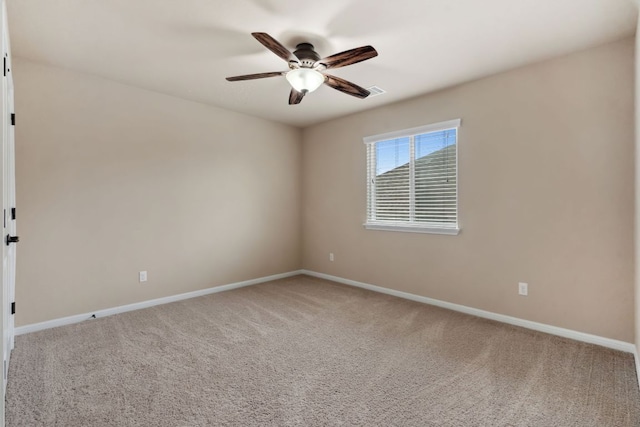 carpeted spare room with ceiling fan and baseboards