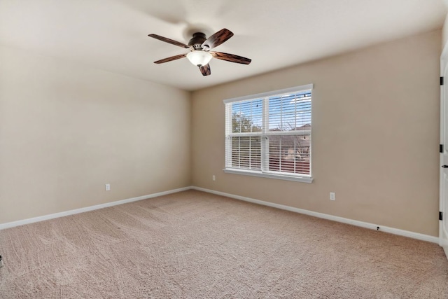 carpeted spare room featuring ceiling fan and baseboards