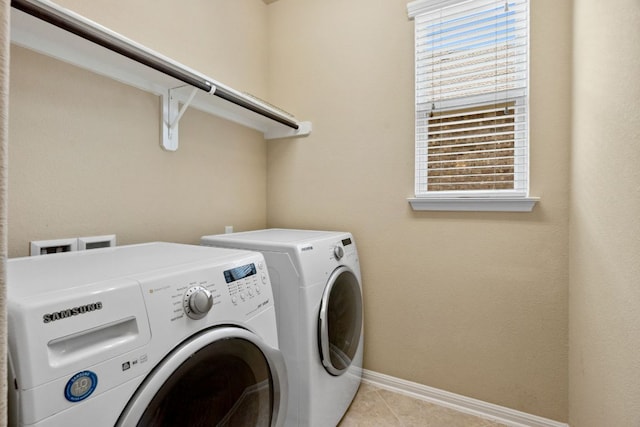 laundry area with a wealth of natural light, laundry area, light tile patterned flooring, and washer and clothes dryer