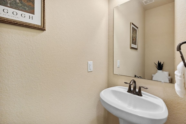 bathroom with visible vents, a sink, and a textured wall