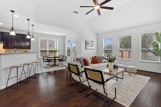 living room with vaulted ceiling, dark wood-style flooring, plenty of natural light, and visible vents