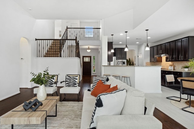 living room with arched walkways, stairs, and light wood-style flooring