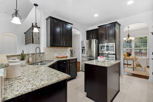 kitchen featuring arched walkways, decorative backsplash, light stone counters, appliances with stainless steel finishes, and a sink